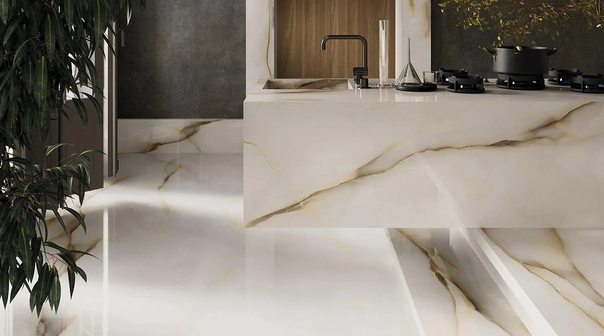 Venetia Onyx White polished porcelain tiles on a kitchen floor and a matching tiled island, with amber and grey veins on a soft white base